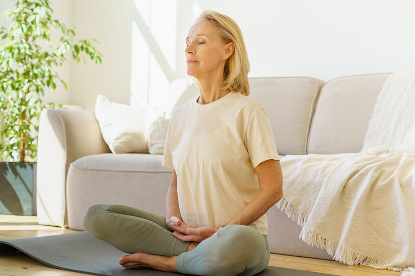 Why A Calm Environment Is An Important Aspect In Dementia Care In   Peaceful Senior Woman In Lotus Position Meditation With Closed Eyes At Home 